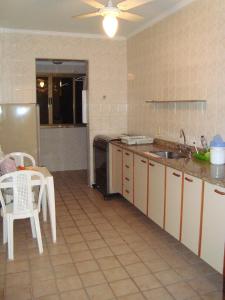 eine Küche mit einer Spüle, einem Tisch und einem Kühlschrank in der Unterkunft Apartamento na Praia Grande em Ubatuba in Ubatuba