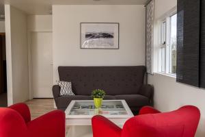 a living room with a couch and red chairs at Vogar Travel Service in Myvatn