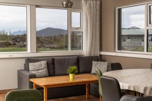 a living room with a couch and a table and windows at Vogar Travel Service in Myvatn