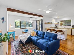 a living room with a blue couch and a kitchen at Iluka Calling in Iluka