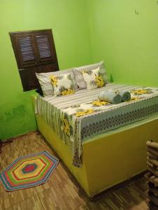 Bett in einem Zimmer mit grüner Wand in der Unterkunft Casa Gael (Gisele & Lucimar) in Atins