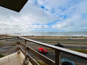 a red car on a parking lot next to the ocean at Departamento A Mar in Mar del Plata