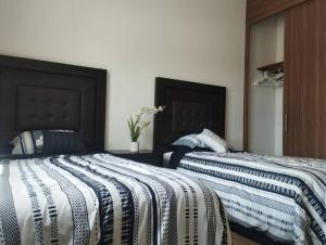 Dos camas una al lado de la otra en un dormitorio. en Hermosa casa a 5 minutos del consulado Americano, cuenta con 3 recamaras, sistema de refrigeración y calefacción, en Ciudad Juárez