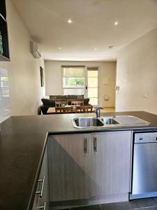 a kitchen with a sink and a living room at Central Shepparton Apartment 13 in Shepparton +4 photos