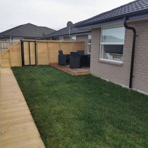 a backyard of a house with a fence and a lawn at Comfort and Peace at The Lakes in Tauranga
