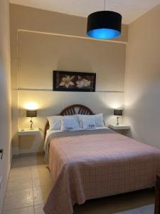 a bedroom with a bed with two tables and a blue light at Temporario Aguilares in Aguilares