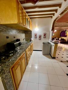 a kitchen with wooden cabinets and a white tile floor at Red House in Essaouira