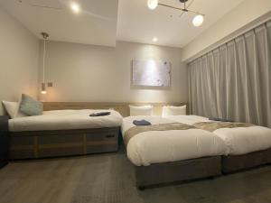 a bedroom with two beds and a couch at Hotel Cordia Osaka Hommachi in Osaka
