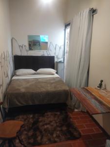 una camera da letto con un letto, un tavolo e una finestra di Recanto das Pedras - Suíte 2 a São Thomé das Letras