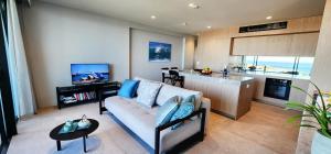 a living room with a couch and a kitchen at Coastal Luxury overlooking Tamarama Beach in Sydney