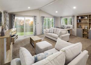 a living room with white couches and a tv at Hamlet Lodge Retreat At Calloose Holiday Park in Hayle
