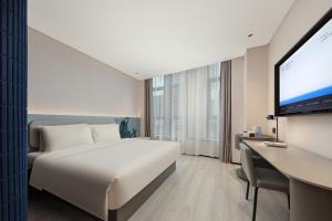 Atour Light Hotel Wuxi Taihu Lake Expo Center Financial Street في ووشي: غرفة فندقية مع سرير وتلفزيون بشاشة مسطحة