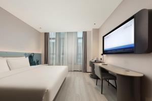 una camera con letto e TV a schermo piatto di Atour Light Hotel Wuxi Taihu Lake Expo Center Financial Street a Wuxi