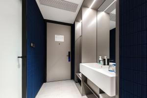 Atour Light Hotel Wuxi Taihu Lake Expo Center Financial Street في ووشي: حمام مع حوض أبيض ومرآة