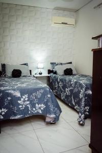 um quarto com duas camas e uma mesa com um abajur em Casa de Gente Feliz 2 em Cuiabá
