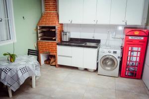 uma cozinha com uma cabine telefônica vermelha e uma máquina de lavar em Casa de Gente Feliz 2 em Cuiabá mais 1 fotografia