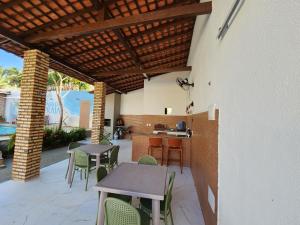 a patio with tables and chairs under a wooden pergola at Casa de Praia Araçagy in Macajatuba