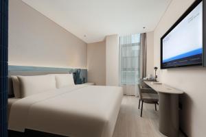 una camera d'albergo con un letto, una scrivania e una TV di Atour Light Hotel Wuxi Taihu Lake Expo Center Financial Street a Wuxi