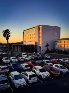 a parking lot full of cars in front of a building at JetPark Auckland Airport Hotel in Auckland