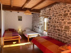 LaprugneにあるMaison de charme à la montagne avec animaux admis - FR-1-489-184の石壁のベッドルーム1室(ベッド2台付)
