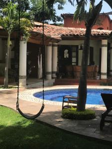 a swing in front of a house with a pool at Finca Las Palmas in Malinalco