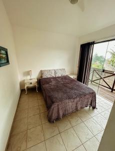 a bedroom with a bed and a large window at Casa Aconchego in Búzios +13 photos
