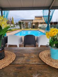 un tavolo in legno con sedie e una piscina di Country Gardens Motel a Coonabarabran