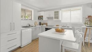 eine weiße Küche mit weißen Schränken und einer Theke in der Unterkunft Woodhill Cottage in Worrowing Heights