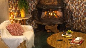 a living room with a fireplace and a chair and a table at Casa de Pedras na Montanha Stone House in Atibaia +7 photos