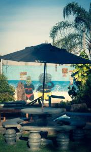 a table with an umbrella in front of a mural at Casa de Pedras na Montanha Stone House in Atibaia