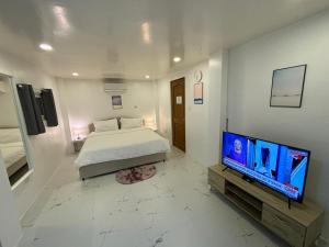 a bedroom with a bed and a flat screen tv at Pinky's Beach House in Victoria