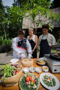 a group of people standing around a table with food at The Artini Dijiwa Ubud in Ubud