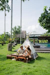 a man and woman sitting at a table in a tent at The Artini Dijiwa Ubud in Ubud