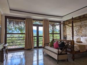 a bedroom with a bed and a couch and windows at Dream Mount Villa in Ella