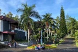 a group of people sitting in front of a building with palm trees at Puncak Villa Lotus D33 in Cipanas