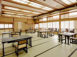 an empty classroom with tables and chairs and windows at Ishikin in Gifu