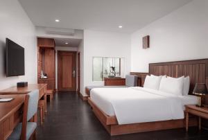 a hotel room with two beds and a desk at Two Seasons Siem Reap Hotel in Siem Reap