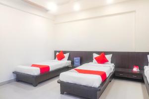 プネにあるHotel O Paradise Inn Talegaon Dabhadeの赤と白の枕が備わる客室内のベッド2台