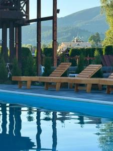 a swimming pool with benches next to the water at Садиба Близнюки in Vorokhta