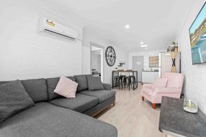 a living room with a gray couch and a pink chair at 2 Cute by Experience Jervis Bay in Huskisson