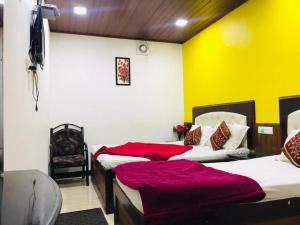 two beds in a room with yellow walls at Hotel mystique inn ooty in Ooty