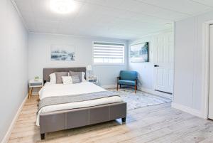 a bedroom with a bed and a blue chair at Luxury Beach Cottage - Maijac Resort & Marina in Burks Falls