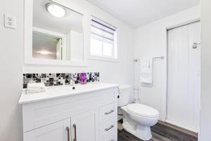 a white bathroom with a toilet and a sink at Luxury Beach Cottage - Maijac Resort & Marina in Burks Falls +35 photos