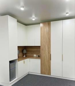 a kitchen with white cabinets and a wooden wall at Juldyz in Zharkent