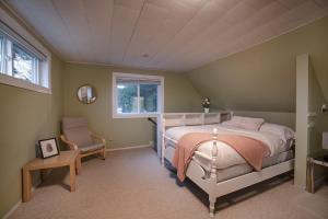 ein Schlafzimmer mit einem Bett und einem Stuhl und einem Fenster in der Unterkunft Muskoka Waterfront Cottage - Moon River with HOT TUB in Bala