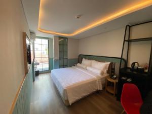 a bedroom with a bed and a red chair at Luxeur Jakarta - Setiabudi in Jakarta