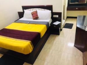 a bedroom with a large bed with yellow sheets at Hotel mystique inn ooty in Ooty