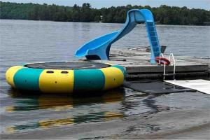 een waterglijbaan en een opblaasboot bij Beachfront Cottage #2- Maijac Resort & Marina in Burks Falls