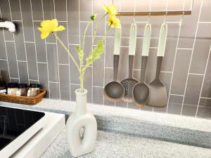 a white vase with flowers in a kitchen with utensils at Songnae Forestay in Bucheon