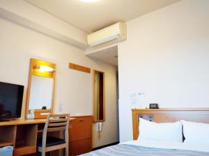 浜松市にあるホテルルートイン浜松西インターのベッドとテレビ付きの机のある部屋